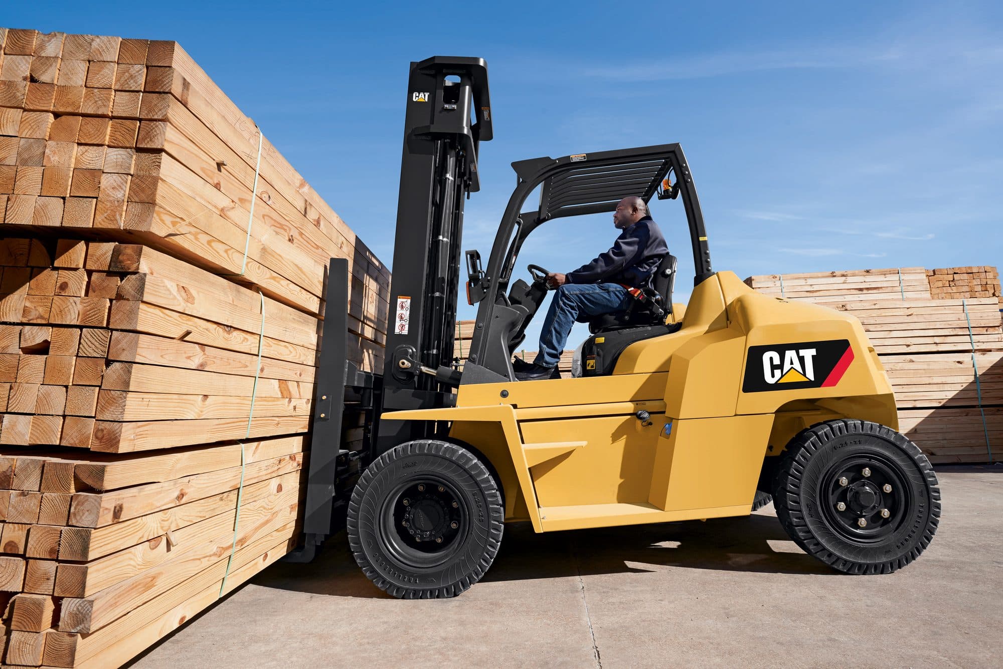 CAT DP70N pneumatic forklift lifting banded lumber in a timber yard