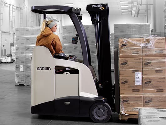Crown RC stand-up forklift moving palletized product in a cold-storage warehouse