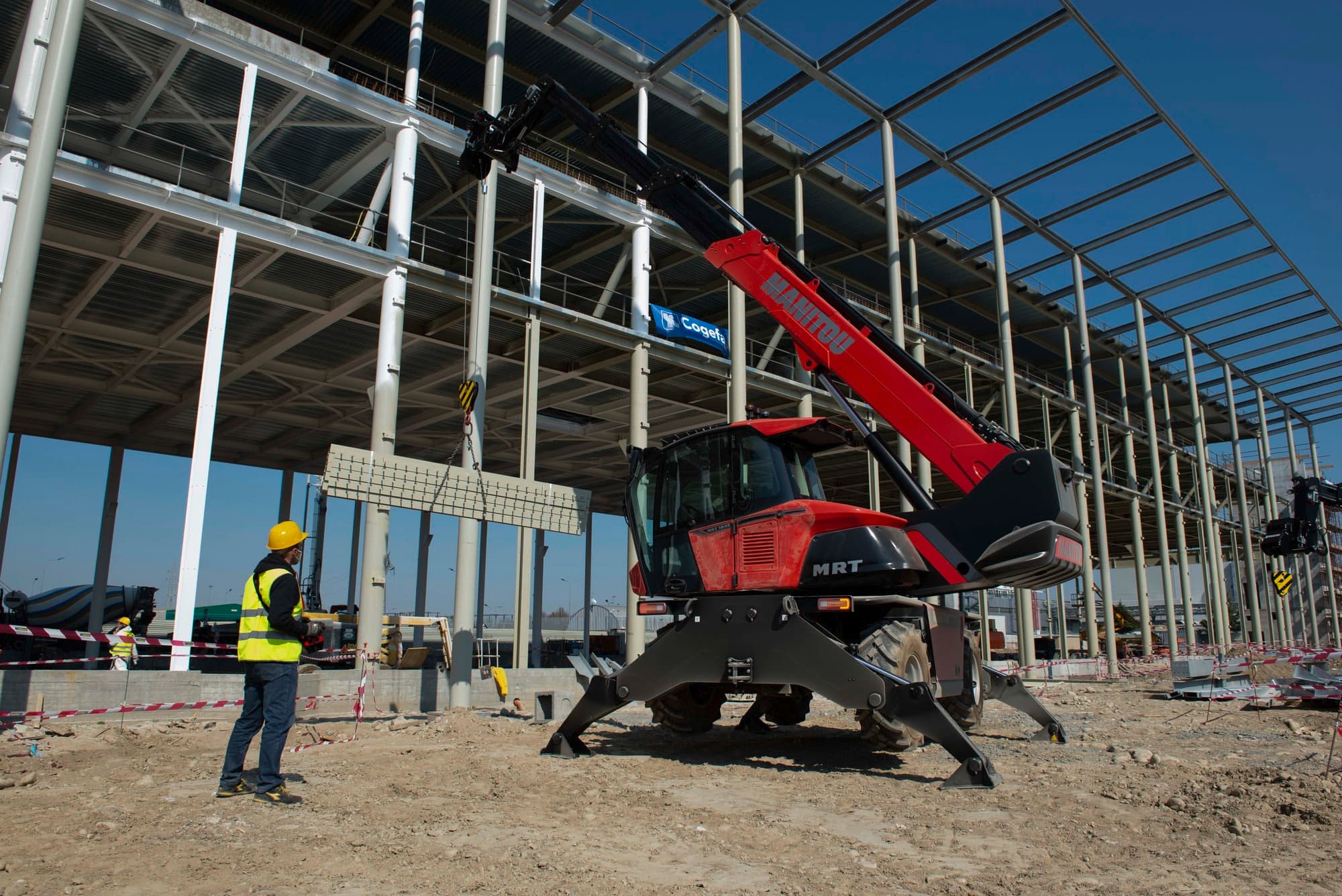 Manitou MRT 1845 rotating telehandler with stabilizers deployed on a steel-frame construction jobsite
