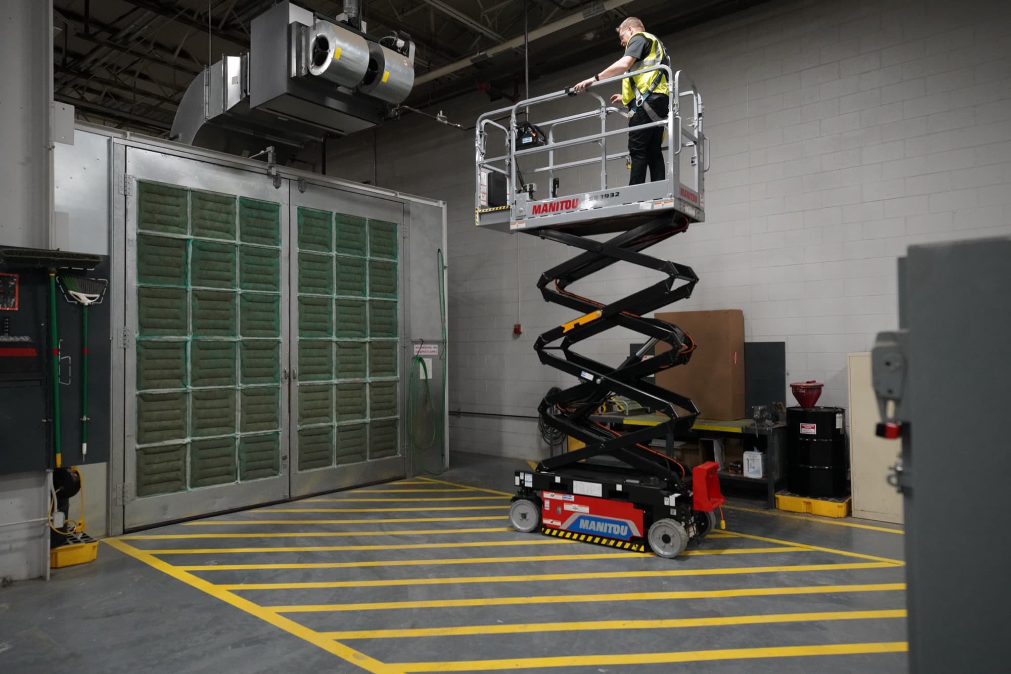 Manitou SE 1932 electric scissor lift extended in an industrial warehouse