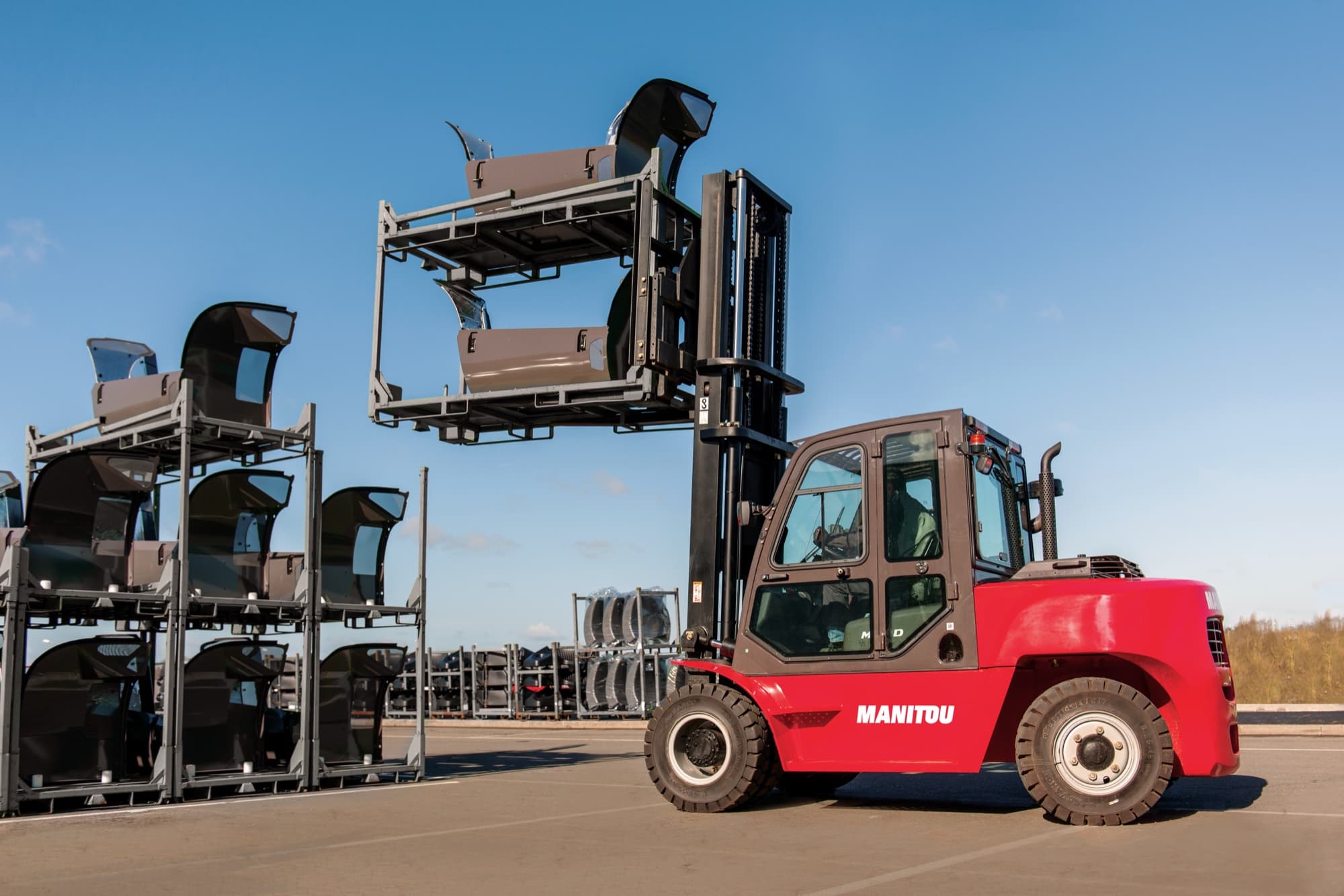 Used Manitou rough-terrain forklift carrying a load in a yard